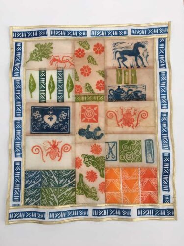 Hand carved stamps printed on tea bags, and are sewn together to create a mini- quilt.